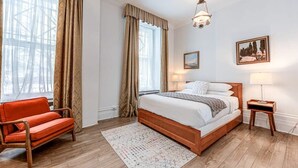A bedroom with a wooden bed, a red sofa, a patterned rug, and two bedside lamps. - Standard Room #3 (Québec)