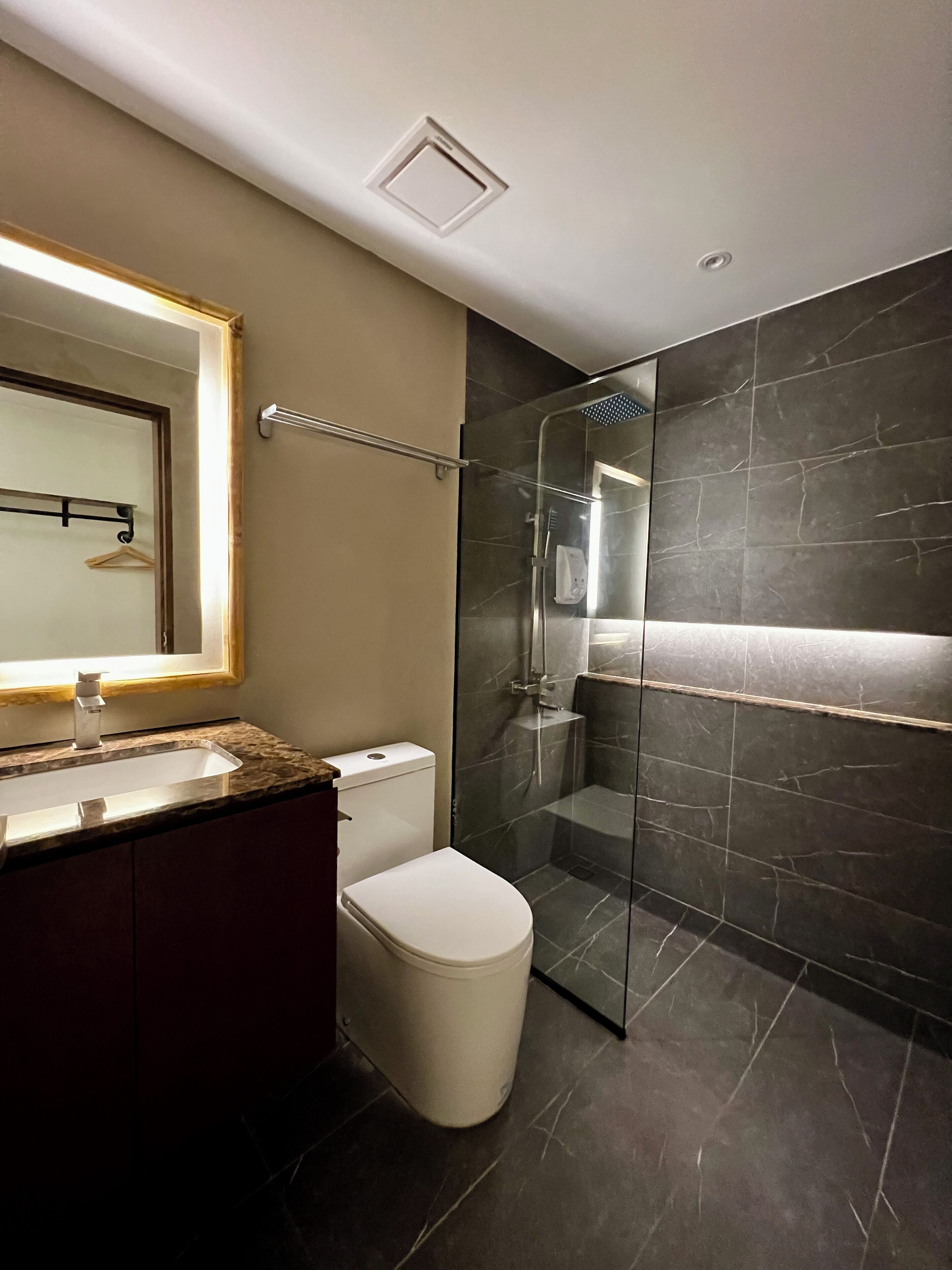 A modern bathroom with a glass-enclosed shower, a toilet, and a vanity with a mirror.