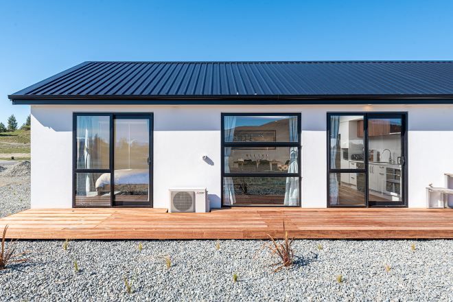 Una casa moderna con tetto piatto, ampie finestre in vetro e un terrazza in legno.