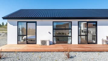 Una casa moderna con tetto piatto, ampie finestre in vetro e un terrazza in legno.