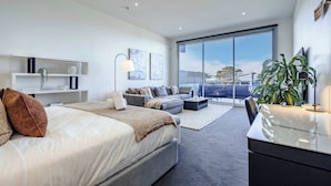Une chambre moderne avec un lit, un canapé, un bureau et une grande fenêtre.
