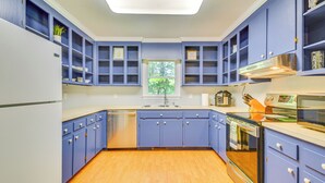 A kitchen with blue cabinets, a stainless steel range hood, and a window with a view of trees. - 15 Mi to Raleigh: Dog-Friendly Home w/ Fire Pit! (Fuquay-Varina)