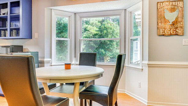 A dining area with a round table, chairs, a blue cabinet, and a window with a view of greenery. - 15 Mi to Raleigh: Dog-Friendly Home w/ Fire Pit! (Fuquay-Varina)
