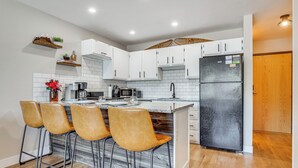 A modern kitchen with white cabinets, a black refrigerator, and a wooden island with bar stools. - Walk to Dtwn: Winter Park Studio w/ Hot Tub Access (Winter Park)