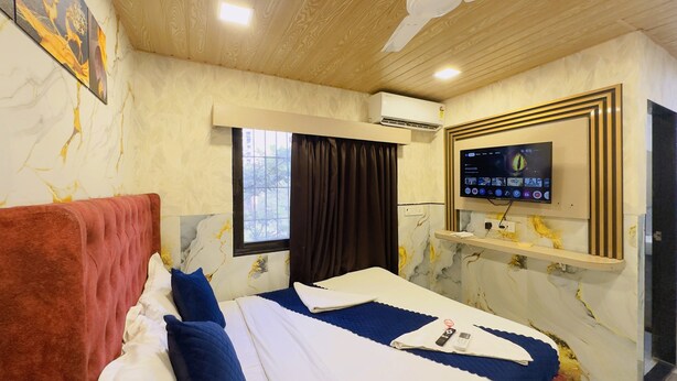 Une chambre d’hôtel avec un lit, un téléviseur fixé au mur, une fenêtre avec des rideaux et un plafond recouvert de panneaux de bois.