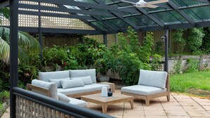 An outdoor patio with a covered seating area, a wooden coffee table, and a potted plant. - Furche Barossa Vineyard & Fireplace  (Stone Well)