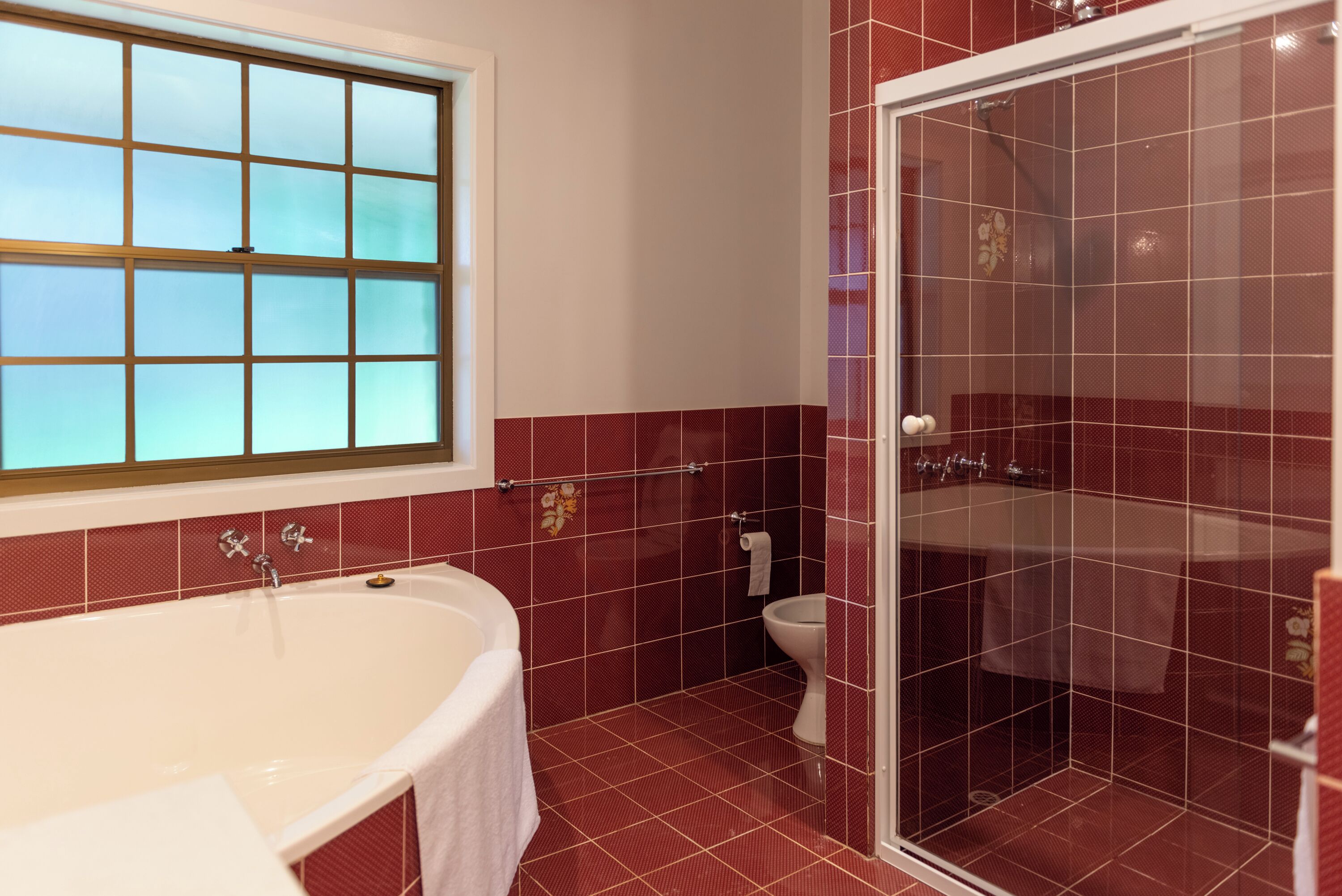 A bathroom with a bathtub, toilet, and glass-enclosed shower.