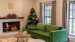 A cozy living room with a green sofa, a fireplace, a Christmas tree, and a large window. - Furche Barossa Vineyard & Fireplace  (Stone Well)