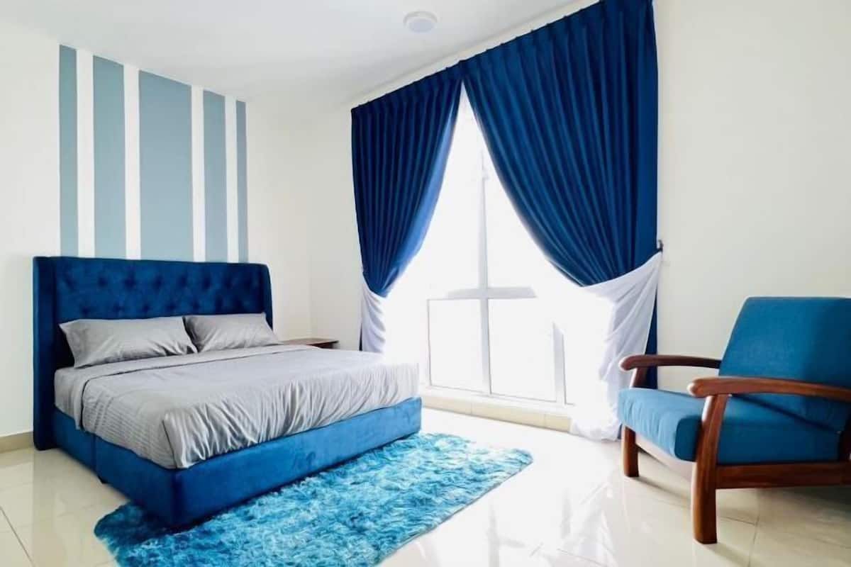 A bedroom with a bed, a chair, and a window with curtains.