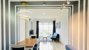 A modern living room with a wooden dining table, white chairs, a blue sofa, and a bench. - KULAI IOI Mall D'Putra Near JPO Senai Airport (Kulai)