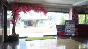 A hotel lobby with a large window, a pink floral arch, and a signboard with information. - SVR Hotel Sai Samrat (Rahata)