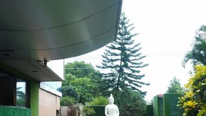 A statue in a garden with a modern building in the background. - SVR Hotel Sai Samrat (Rahata)