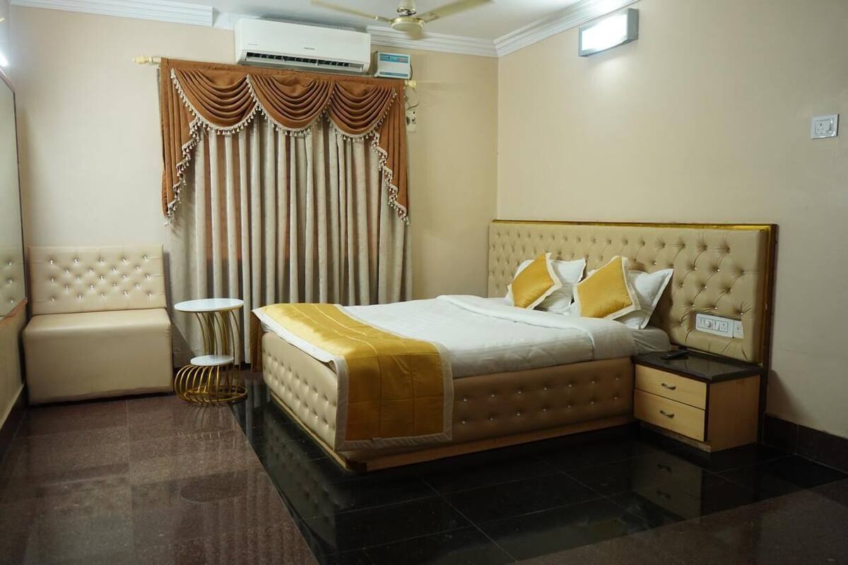 A hotel room with a large bed, a sofa, a small table, and a bedside table.
