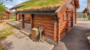Eine Holzhütte mit einem Gründach, einer Veranda und einer kleinen Sitzgelegenheit im Freien.