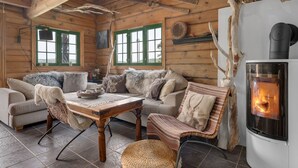 Ein gemütliches Blockhaus-Interieur mit Kamin, Holzwänden und einer komfortablen Sitzecke.