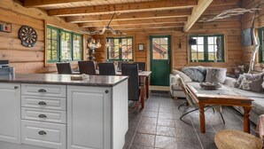 Ein rustikales Blockhaus im Inneren mit Küche, Essbereich und Wohnzimmer.