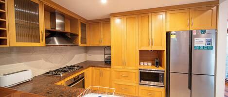 A kitchen with wooden cabinets, stainless steel appliances, a toaster, and a dish rack.