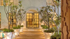 A well-lit entrance with a tiled floor, large potted plants, and a decorative archway.