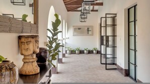 A hallway with a wooden ceiling, potted plants, and a modern door with glass panels.