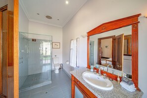 A bathroom with a glass shower enclosure, a sink with a wooden vanity, and a large mirror. - Condor Estate with Vineyard & Fireplace (Maslin Beach)