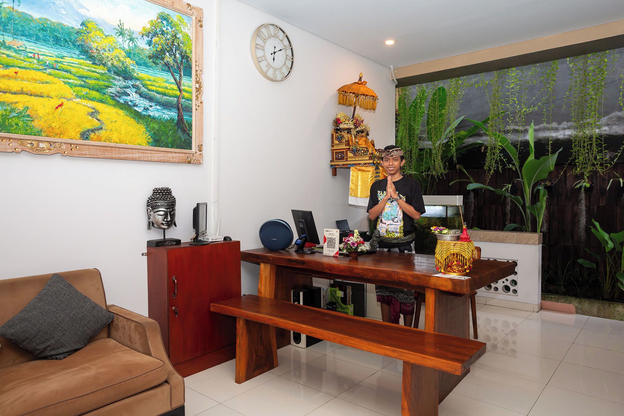 A modern living room with a wooden coffee table, a sofa, a Buddha statue, and a wall clock.