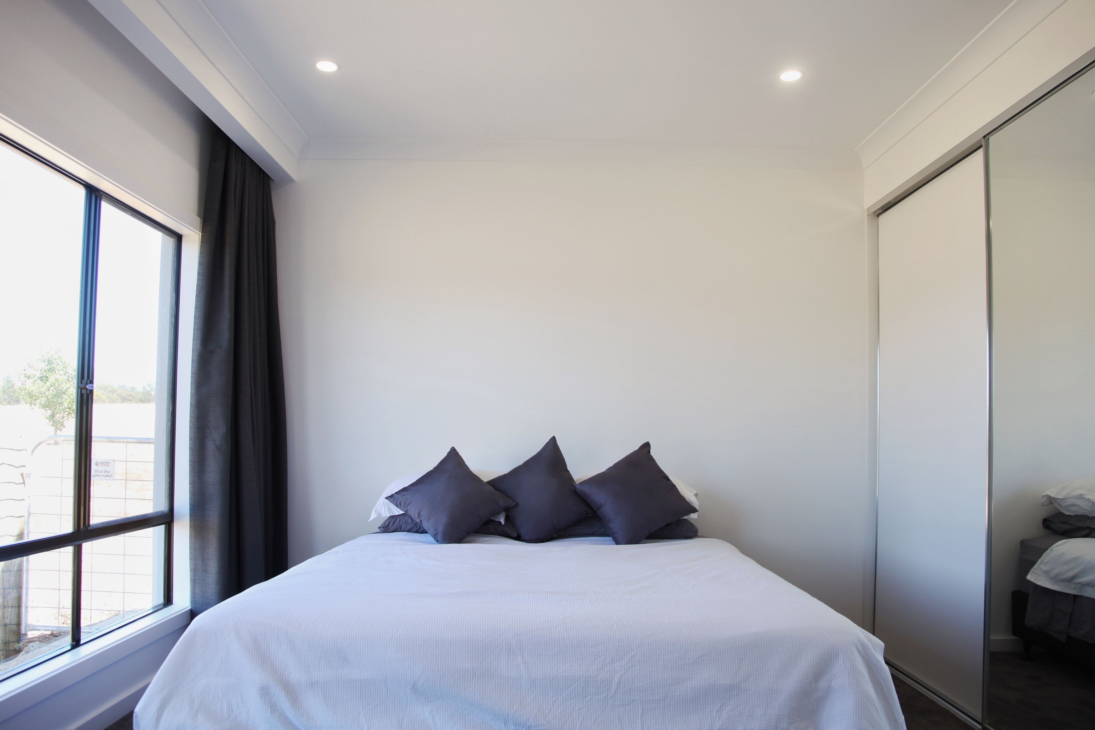 A bedroom with a large bed, a window, and a sliding door.