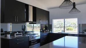 Una cocina moderna con armarios oscuros, una estufa a gas y un amplio ventanal con vistas al exterior.