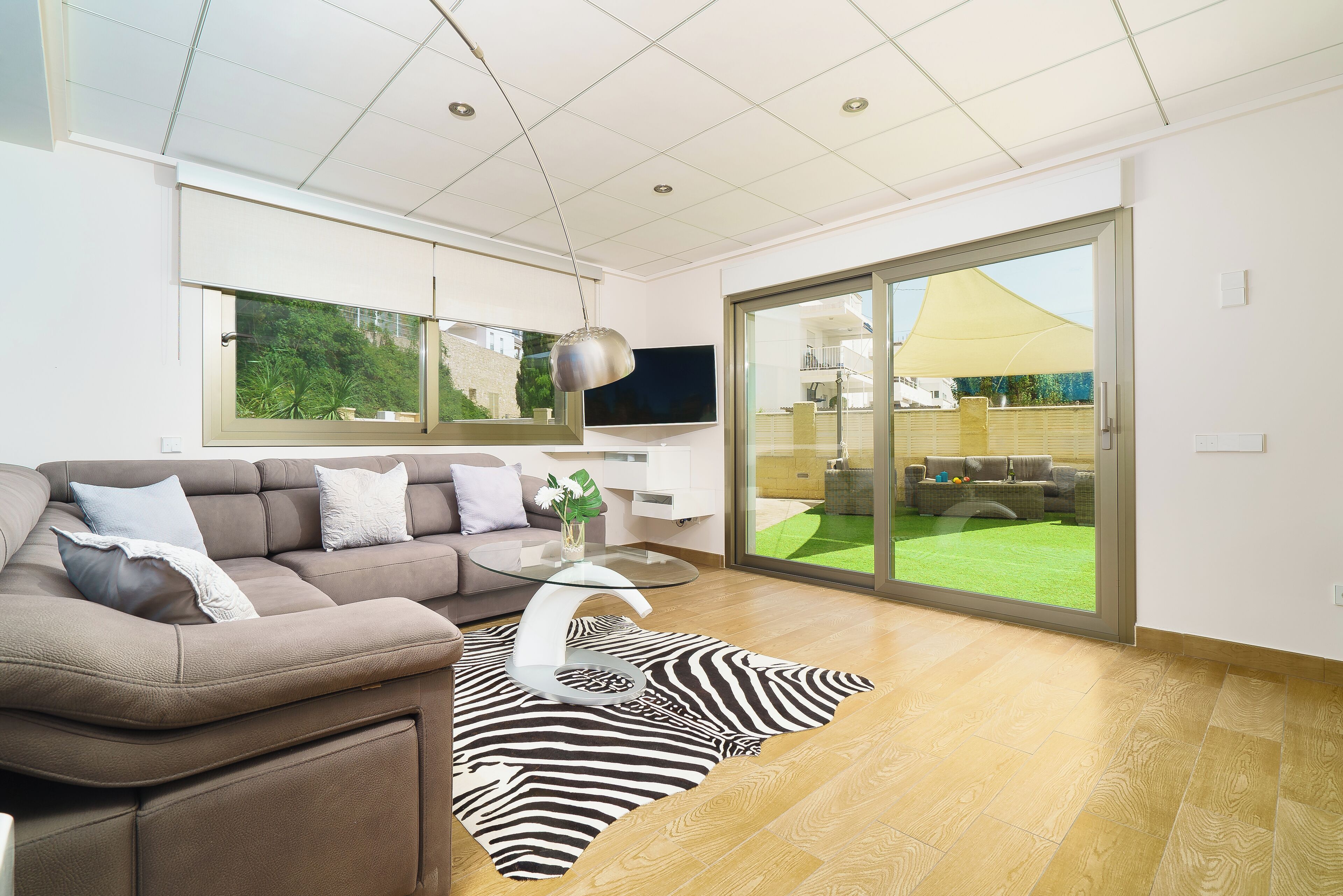 A modern living room with a sectional sofa, a glass coffee table, and a zebra-patterned rug.