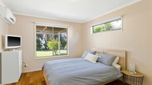 Una camera da letto con un letto, una TV, un tavolino e una finestra vista verde.