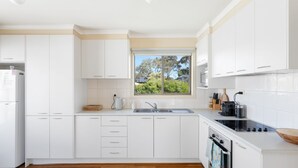 Una cucina moderna con mobili bianchi, forno integrato e una finestra che si affaccia sul verde.
