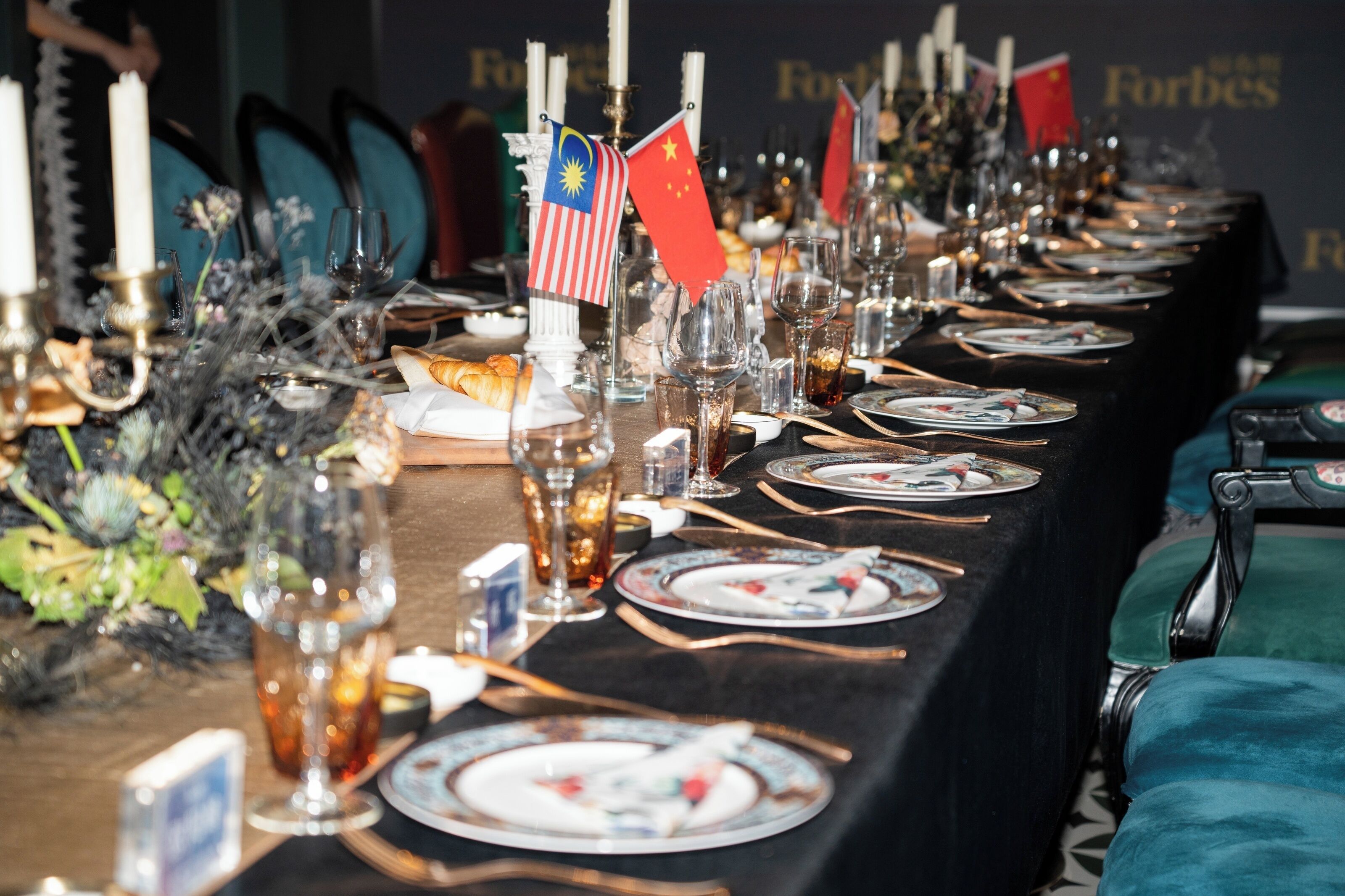 A long dining table set with plates, glasses, and flags.