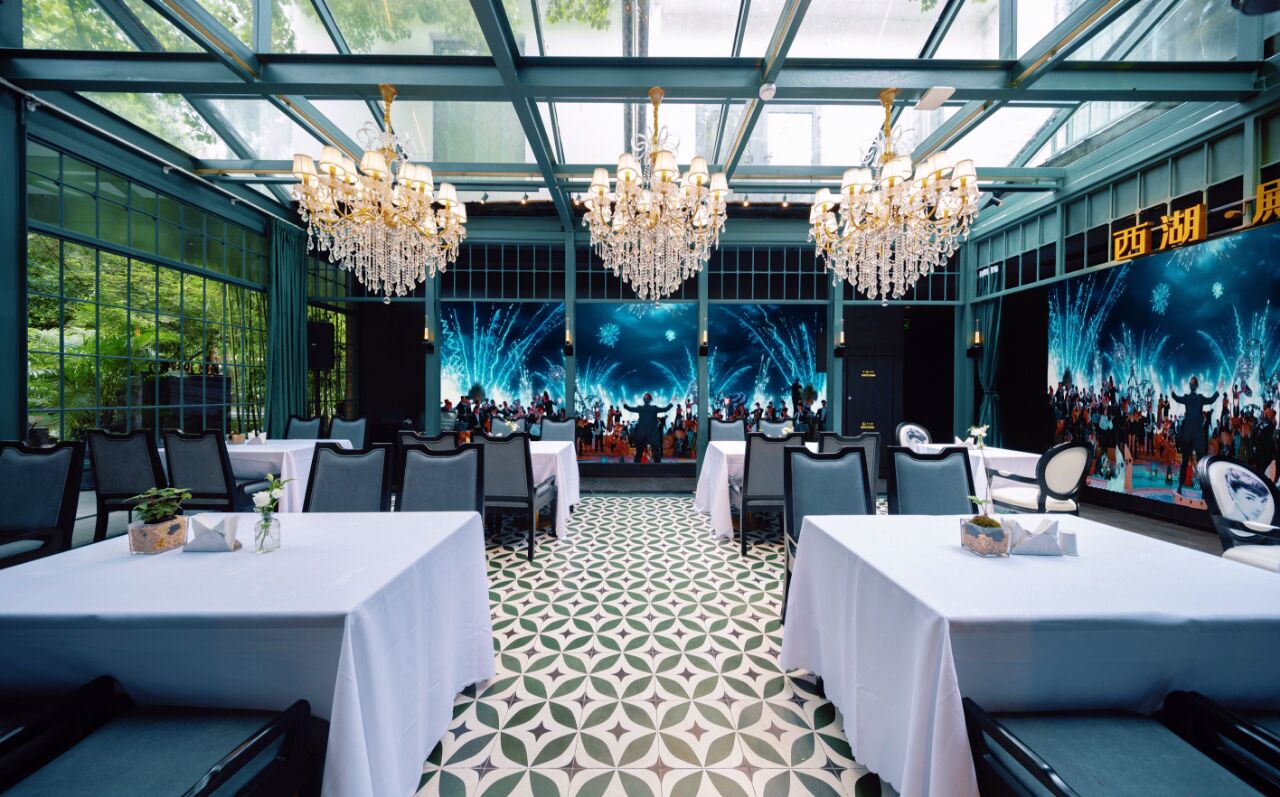 A restaurant with a glass ceiling, chandeliers, and a patterned floor.