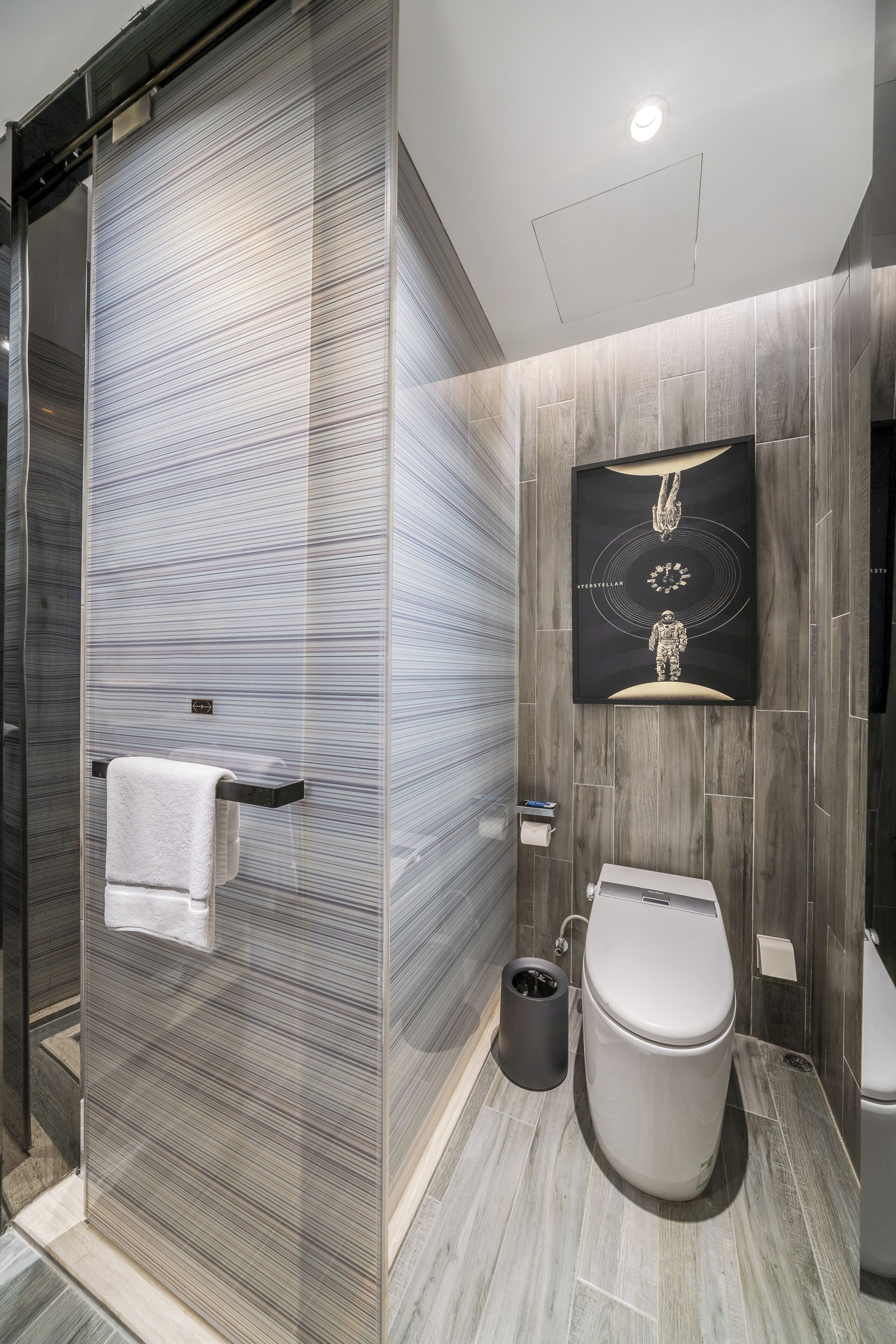 A modern bathroom with a glass shower enclosure, a toilet, and a wall-mounted sink.