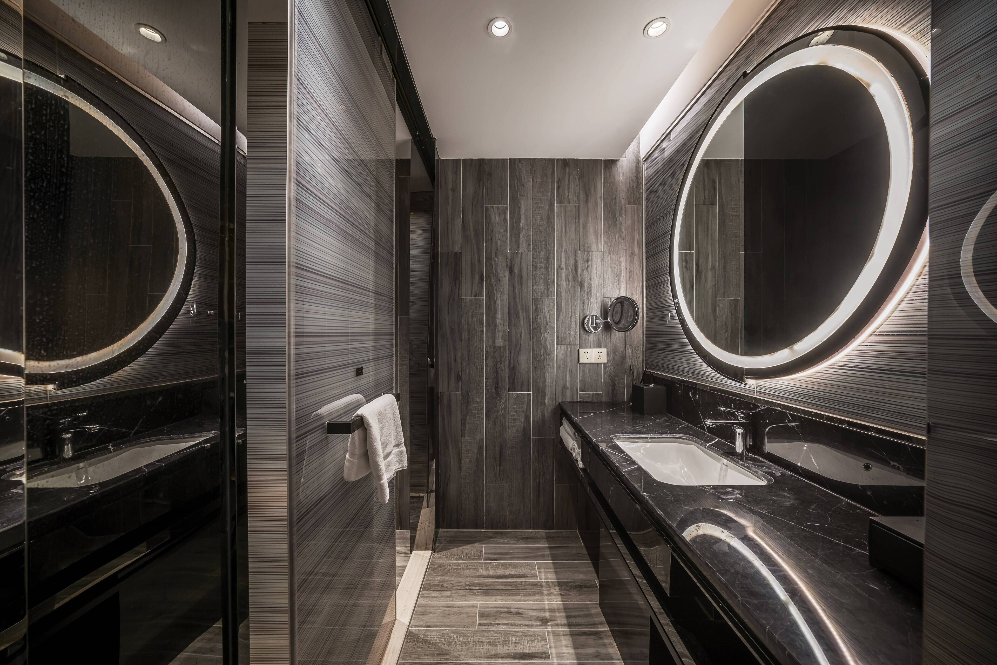 A modern bathroom with two sinks, a large mirror, and a shower area.