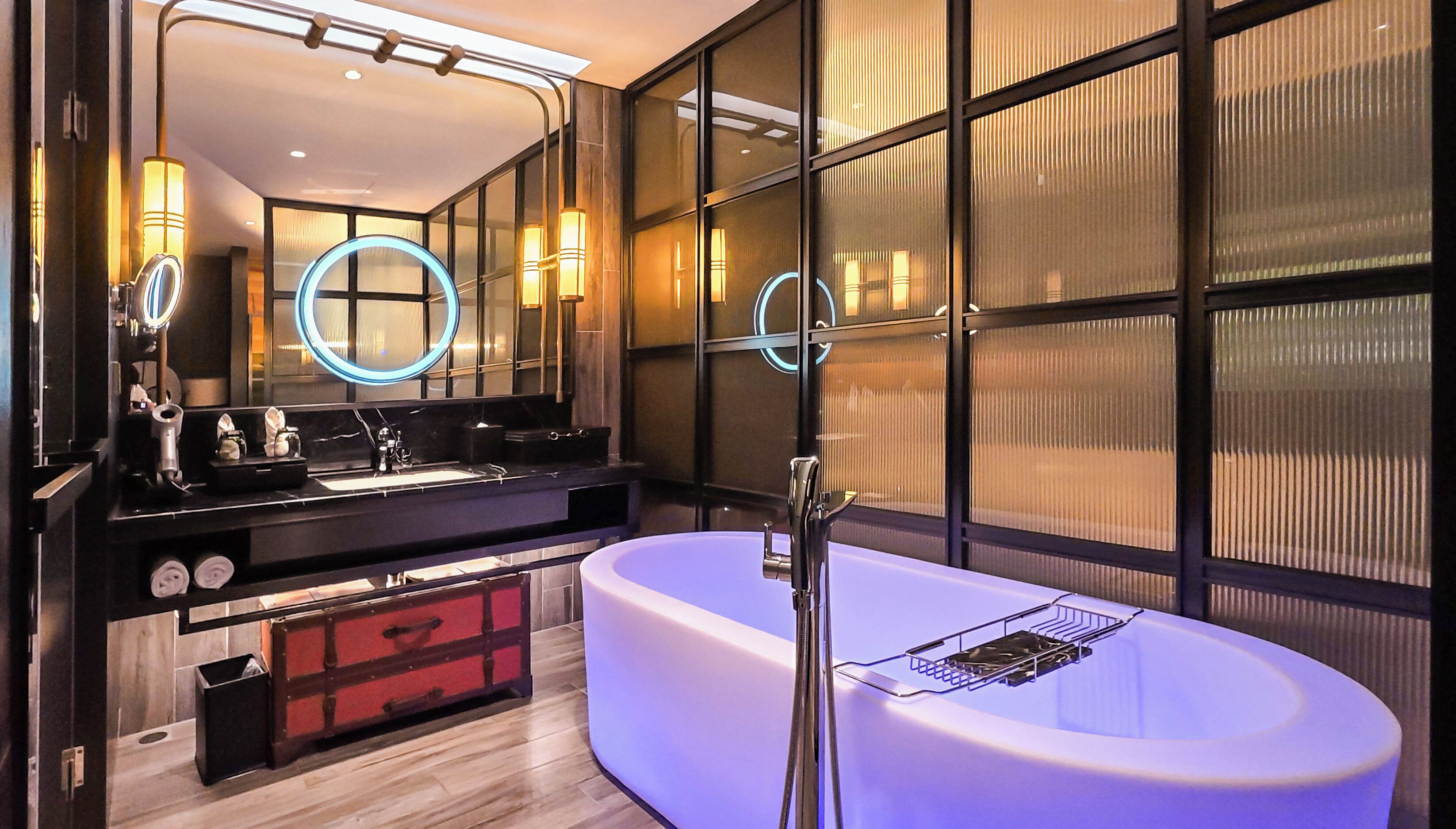 A modern bathroom with a large bathtub, a double sink vanity, and a large mirror.