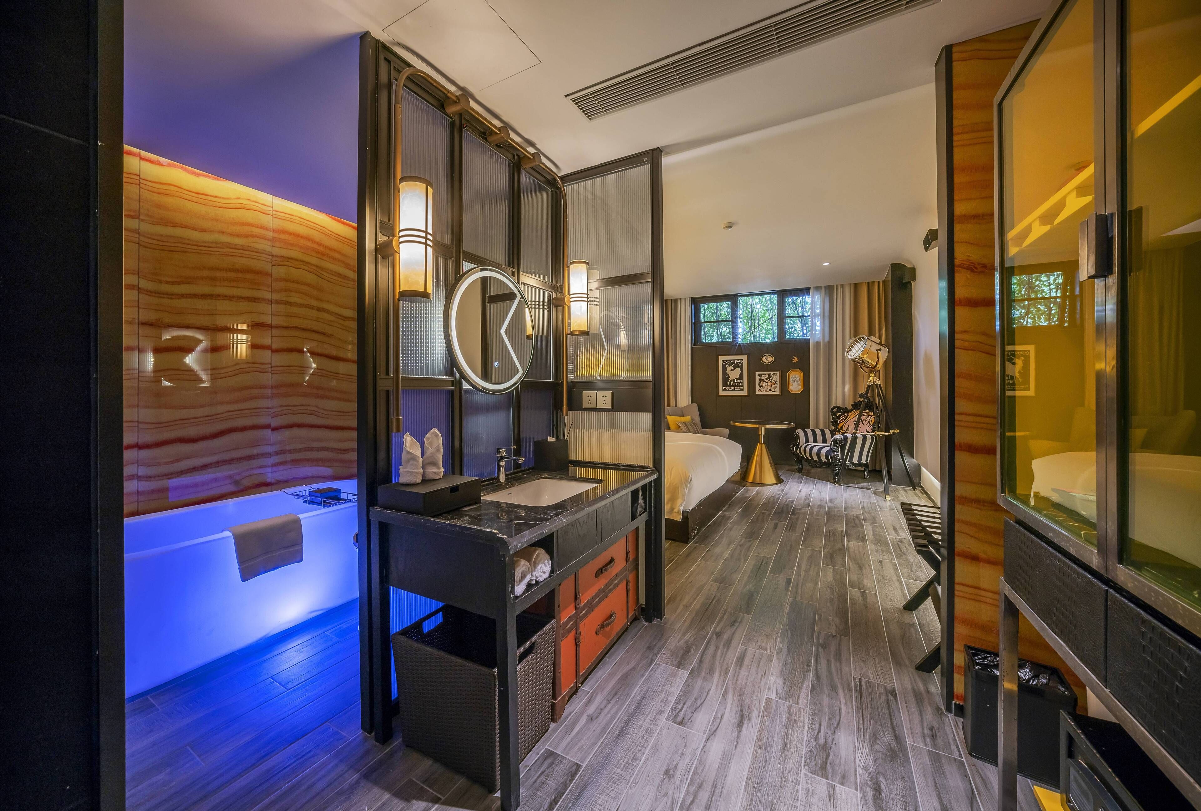 A modern hotel room with a large bed, a separate bathroom with a bathtub, and a large mirror.