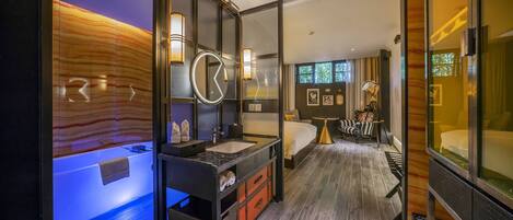 A modern hotel room with a large bed, a separate bathroom with a bathtub, and a large mirror.
