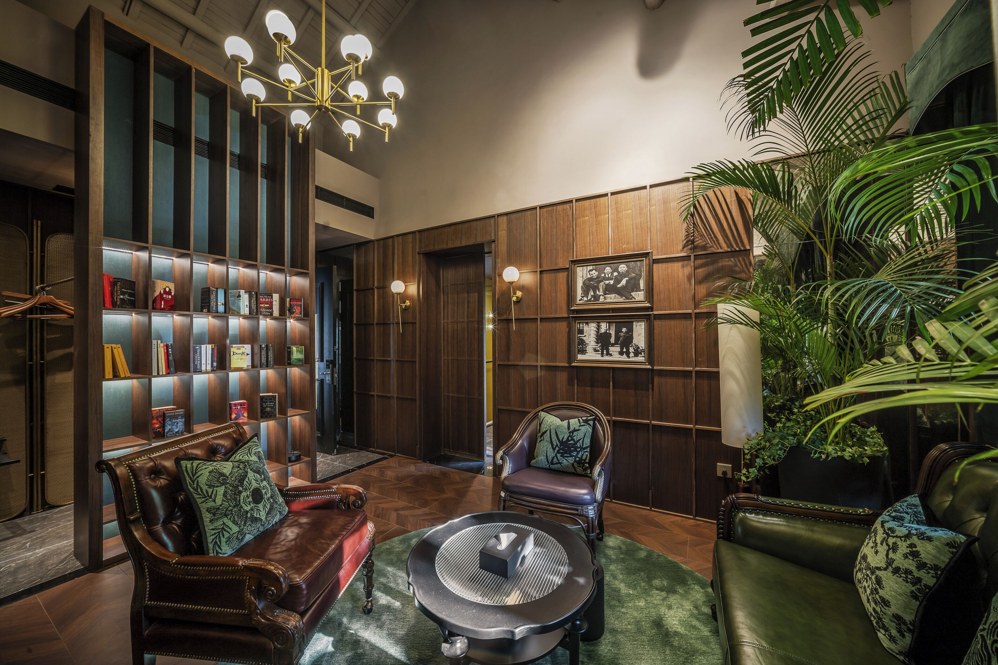 A room with a fireplace, leather sofas, a bookshelf, and a large potted plant.