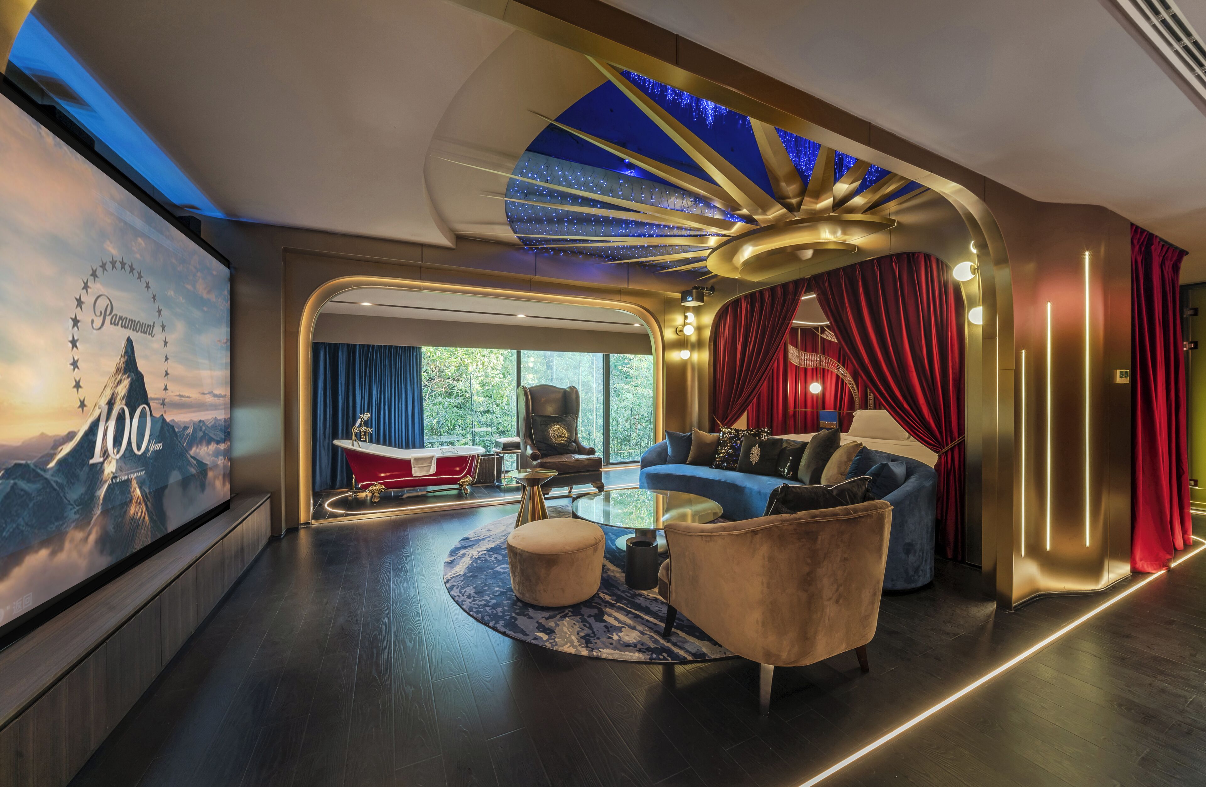 A luxurious living room with a modern design, a large screen, a red bathtub, and a view of the outdoors.