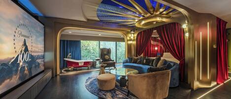 Uma sala de estar luxuosa com design moderno, uma tela grande, uma banheira vermelha e vista para o exterior.