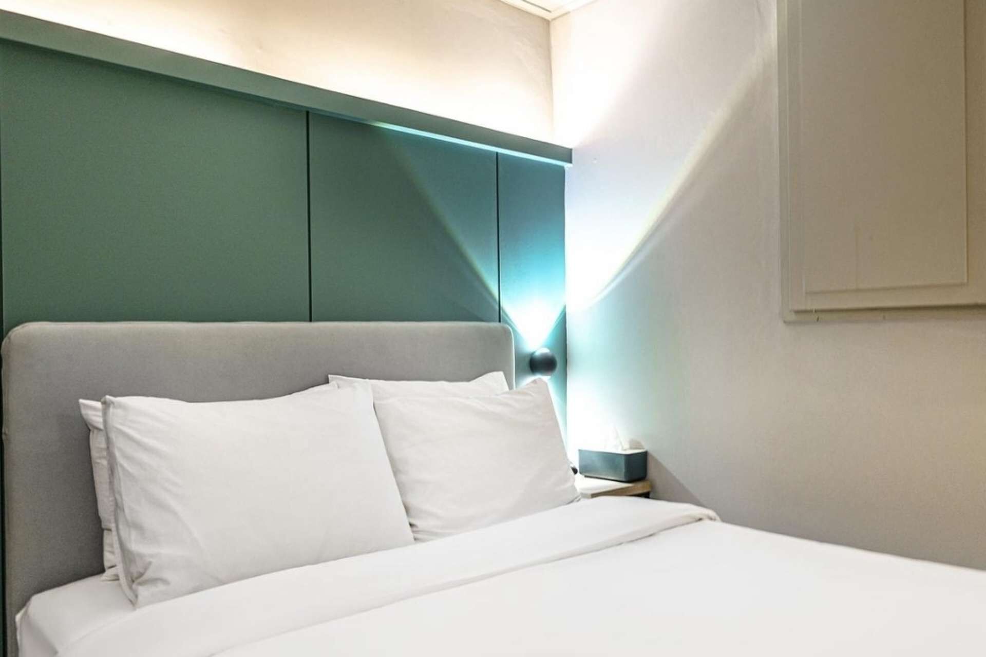 A neatly made bed with white linens in a hotel room.