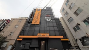 Un edificio de hotel con un letrero llamativo que dice "HOTEL YAM" y un estandarte amarillo.
