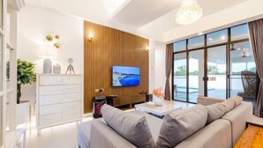 A modern living room with a sofa, a TV, and a large window.