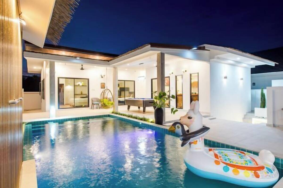 Ein modernes Haus mit Swimmingpool, Essbereich und Kinderspielbereich.