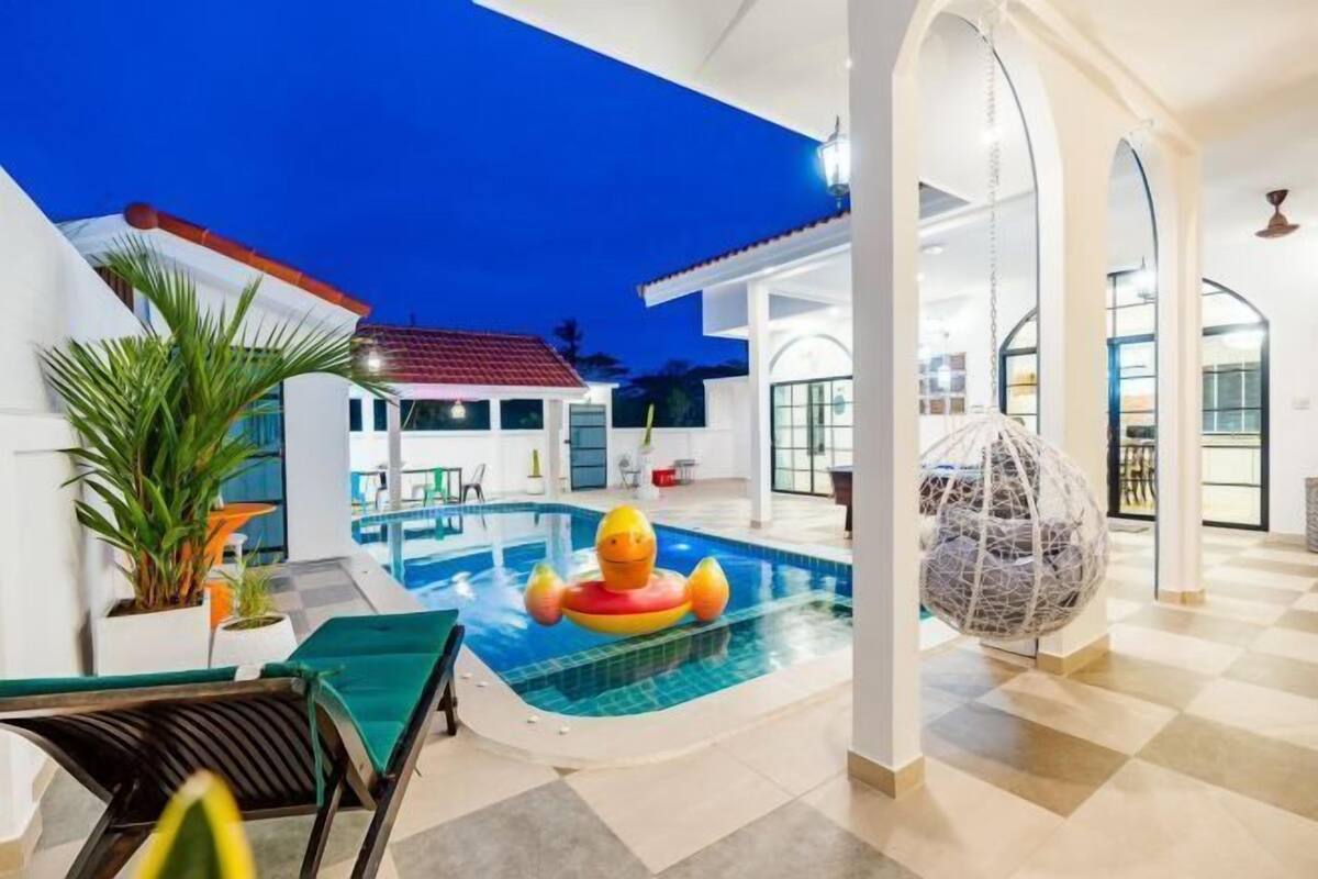 Ein Schwimmbecken mit einer Enten-Schwimmnudel, Liegestühlen und einem dekorativen Ball.