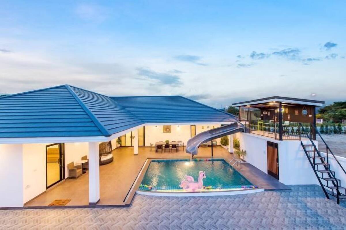 Ein modernes Gebäude mit Schwimmbad, Rutsche und überdachter Terrasse.