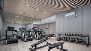 Un gimnasio moderno con cintas de correr, una prensa de banca y un estante con mancuernas.