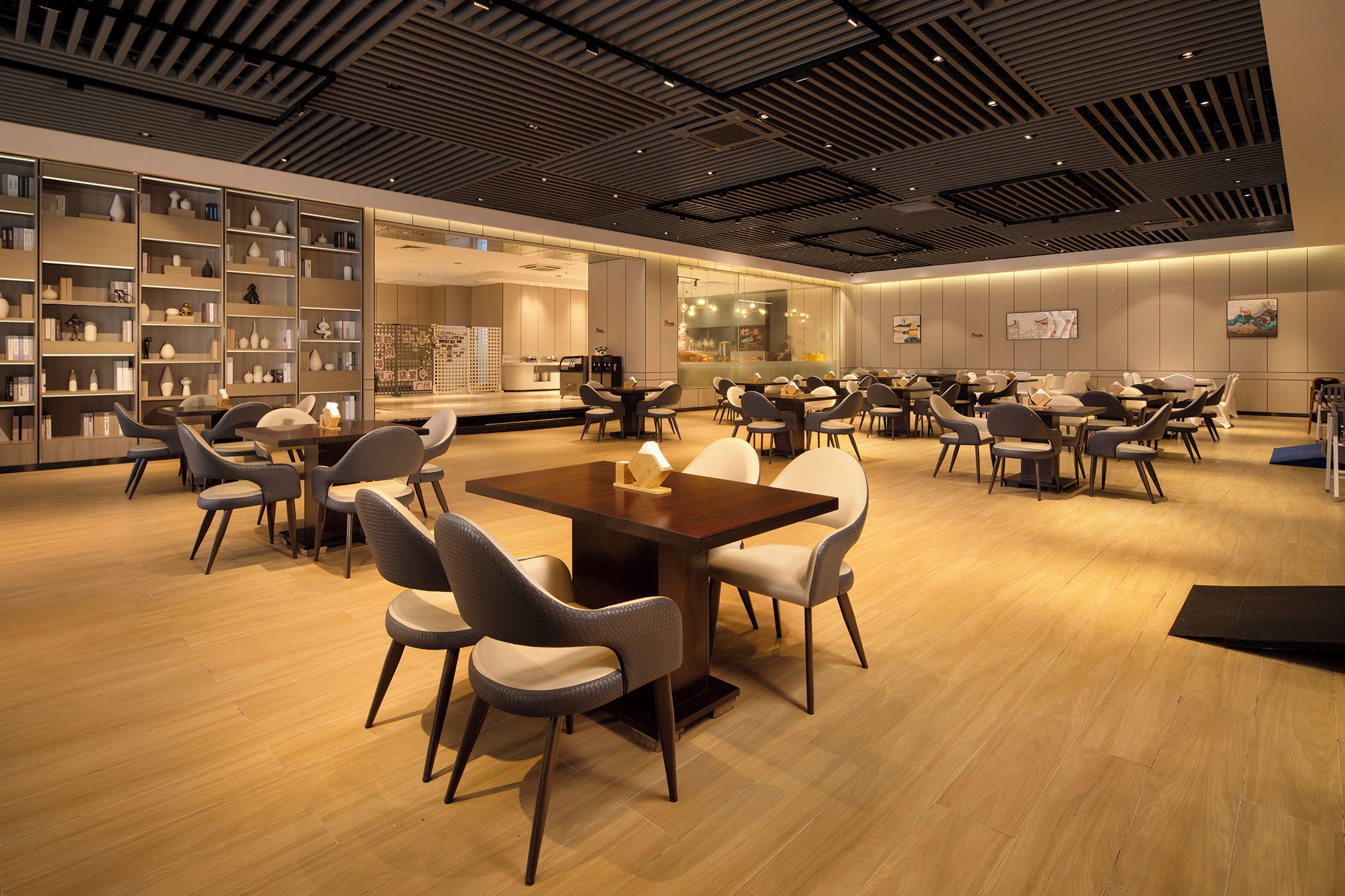 A modern interior with a central dining area, surrounded by bookshelves and a bar area.