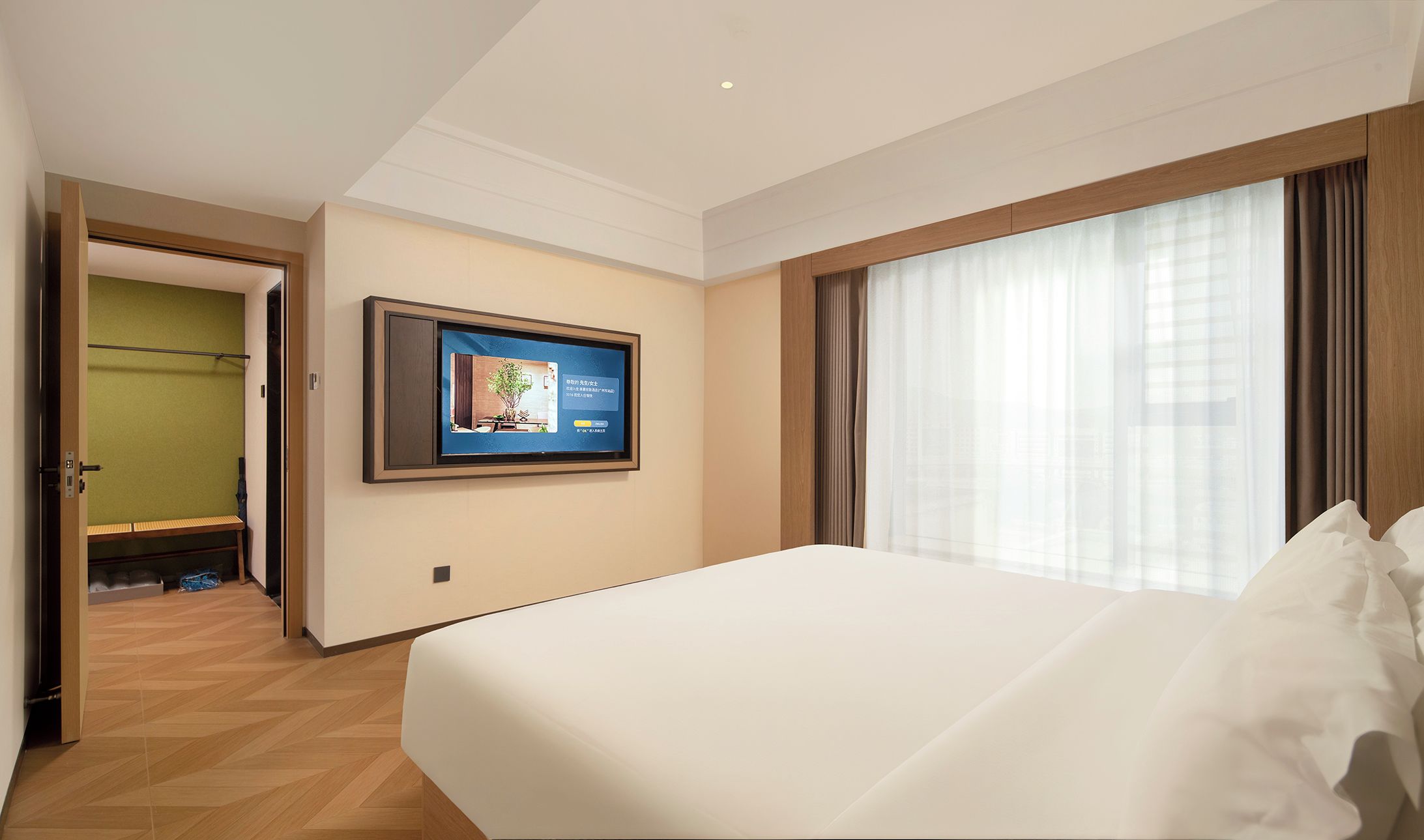 Een hotelkamer met een groot bed, een aan de muur bevestigde televisie en uitzicht op de stad.