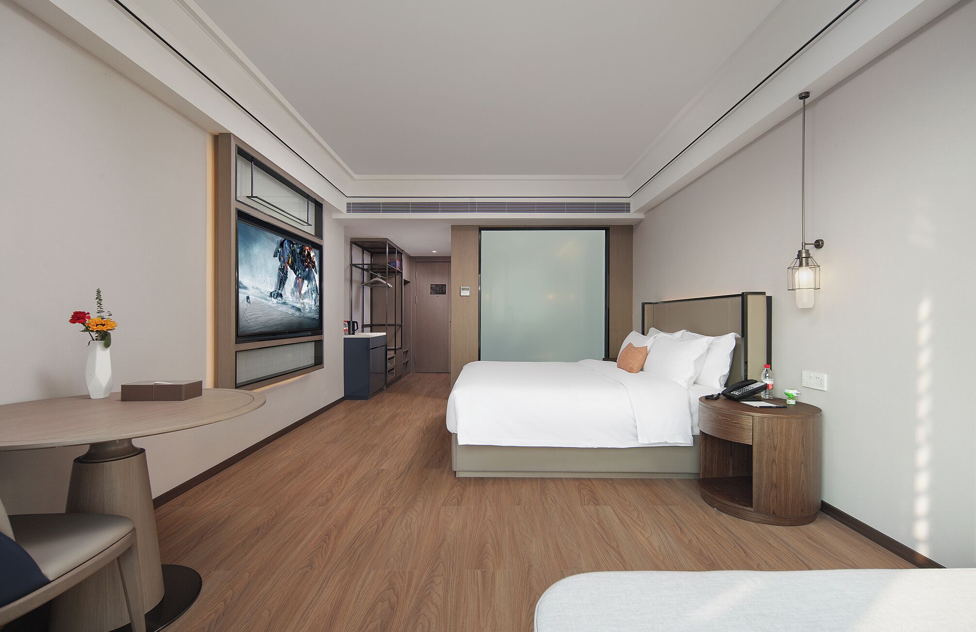 Une chambre d’hôtel comprenant un lit, une table de chevet, une télévision, une armoire et un petit bureau avec une chaise.